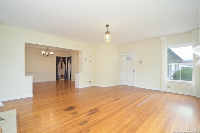 unfurnished living room featuring a chandelier and light wood-type flooring