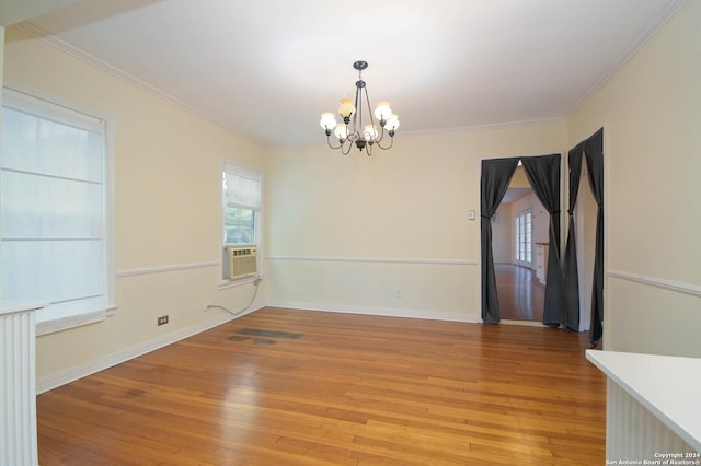 spare room featuring a notable chandelier, cooling unit, light wood-type flooring, and crown molding