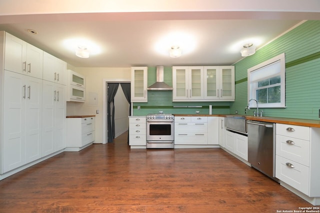 kitchen with white cabinets, dark hardwood / wood-style floors, wall chimney range hood, and stainless steel appliances