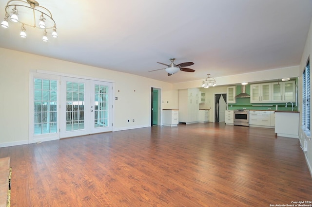 unfurnished living room with ceiling fan with notable chandelier, dark hardwood / wood-style flooring, sink, and french doors