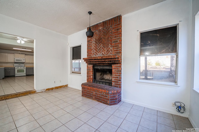 unfurnished living room featuring ceiling fan, light tile patterned floors, a textured ceiling, and a brick fireplace