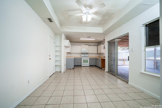 kitchen with white appliances, a raised ceiling, sink, light tile patterned floors, and white cabinetry