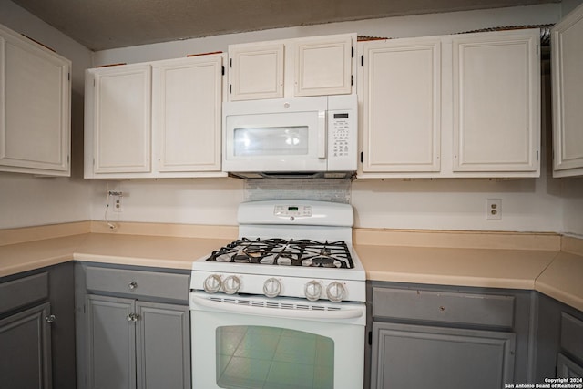 kitchen featuring gray cabinetry, white cabinets, and white appliances