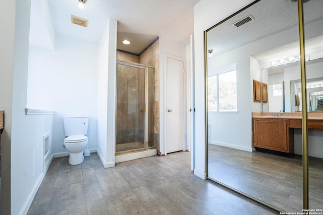 bathroom with hardwood / wood-style flooring, vanity, toilet, and a shower with door