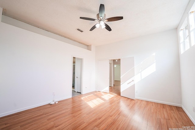 spare room with ceiling fan, light hardwood / wood-style floors, and a textured ceiling