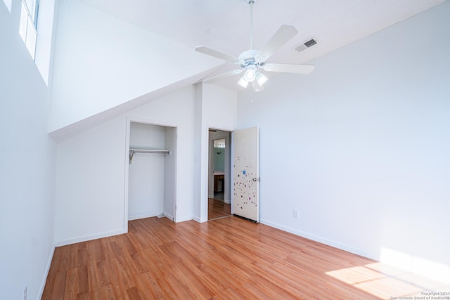 unfurnished bedroom featuring ceiling fan, a closet, high vaulted ceiling, and light wood-type flooring