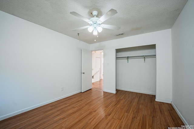 unfurnished bedroom with ceiling fan, a closet, a textured ceiling, and hardwood / wood-style flooring