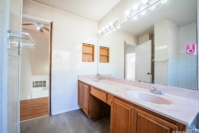 bathroom with ceiling fan, hardwood / wood-style floors, a textured ceiling, vanity, and tile walls