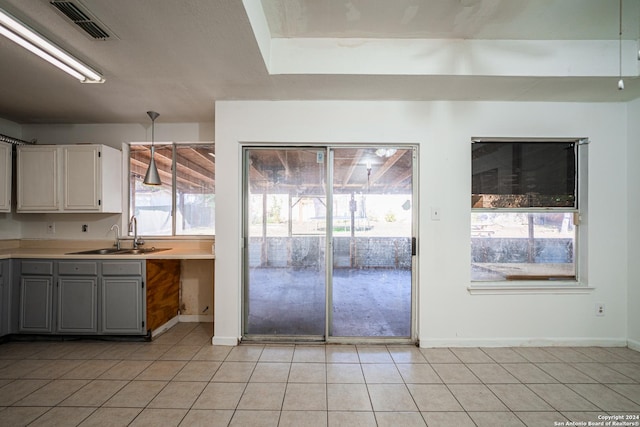 kitchen featuring light tile patterned flooring, gray cabinets, a wealth of natural light, and sink