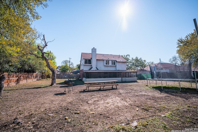 back of property with a sunroom and a trampoline