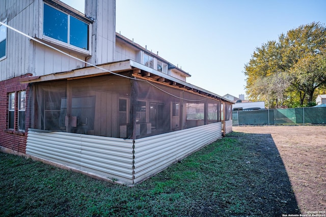 view of property exterior with a yard and a sunroom