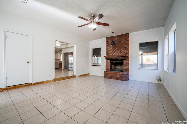 unfurnished living room featuring a fireplace, a textured ceiling, ceiling fan, and light tile patterned flooring