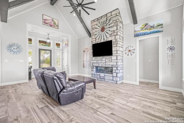 living room featuring high vaulted ceiling, a stone fireplace, ceiling fan, light wood-type flooring, and beamed ceiling