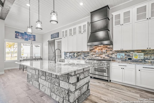 kitchen with premium range hood, sink, a center island with sink, range with two ovens, and white cabinets