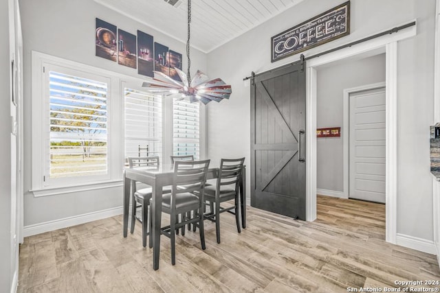 dining space featuring ceiling fan, a barn door, wooden ceiling, and light hardwood / wood-style flooring