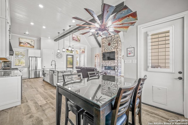 dining space with lofted ceiling, wooden ceiling, sink, light wood-type flooring, and a fireplace