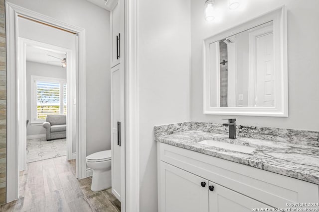 bathroom with hardwood / wood-style flooring, ceiling fan, toilet, and vanity