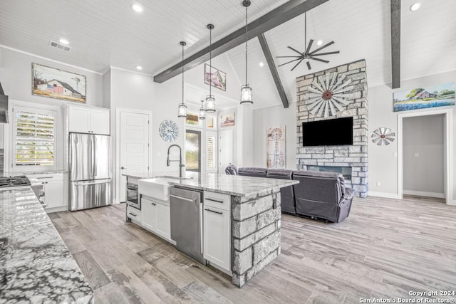 kitchen with a stone fireplace, white cabinets, pendant lighting, and appliances with stainless steel finishes