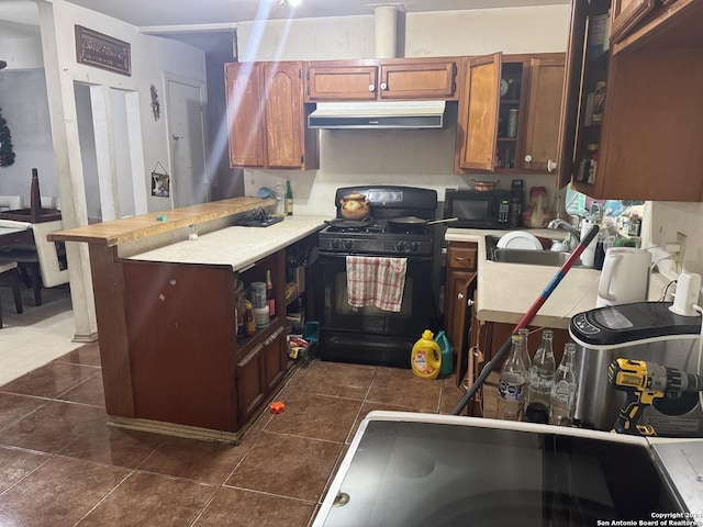 kitchen with sink, dark tile patterned floors, and black appliances