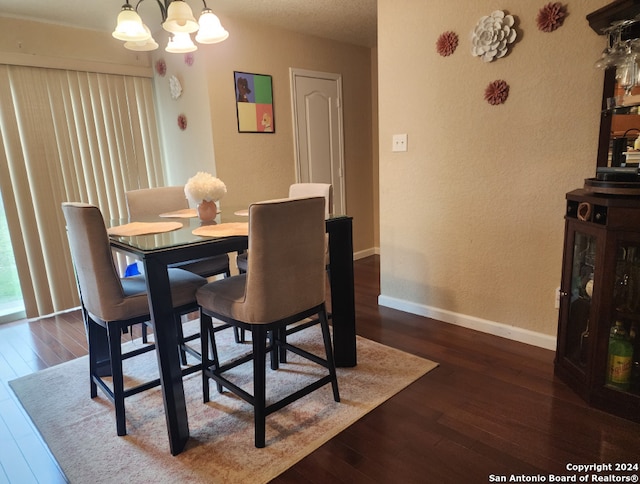 dining space with dark wood-type flooring and a notable chandelier