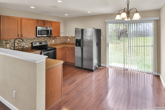 kitchen with an inviting chandelier, tasteful backsplash, kitchen peninsula, pendant lighting, and appliances with stainless steel finishes