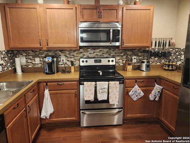 kitchen featuring appliances with stainless steel finishes, tasteful backsplash, dark wood-type flooring, and sink