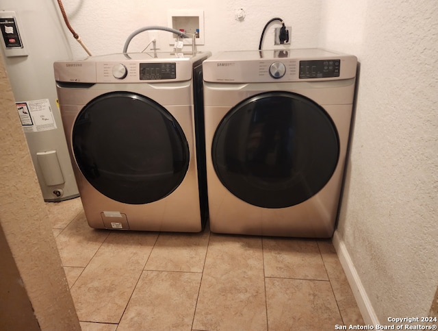 clothes washing area featuring light tile patterned floors, electric water heater, and separate washer and dryer