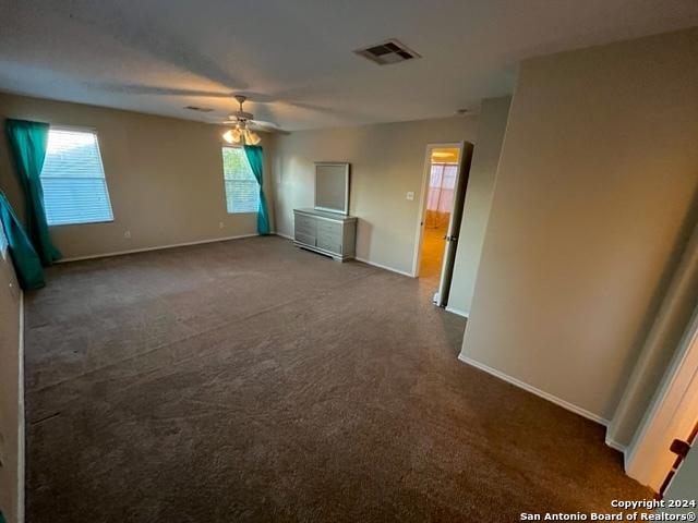 carpeted spare room featuring plenty of natural light and ceiling fan