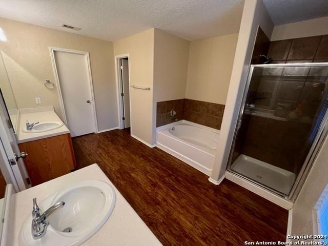 bathroom with vanity, wood-type flooring, a textured ceiling, and shower with separate bathtub