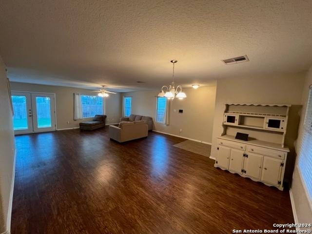 unfurnished living room featuring a textured ceiling, ceiling fan with notable chandelier, dark wood-type flooring, and french doors