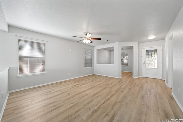 unfurnished living room with a textured ceiling, light hardwood / wood-style floors, and ceiling fan