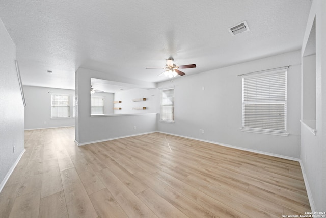 empty room with a textured ceiling, light hardwood / wood-style floors, and ceiling fan