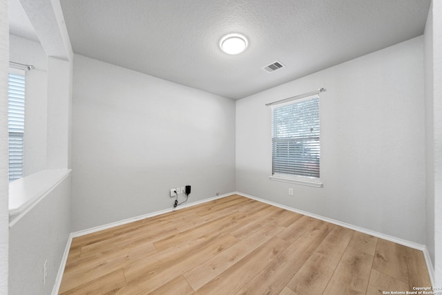 unfurnished room featuring wood-type flooring and a textured ceiling