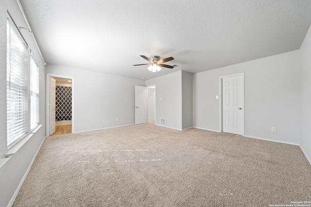 unfurnished room featuring a textured ceiling, ceiling fan, and light carpet