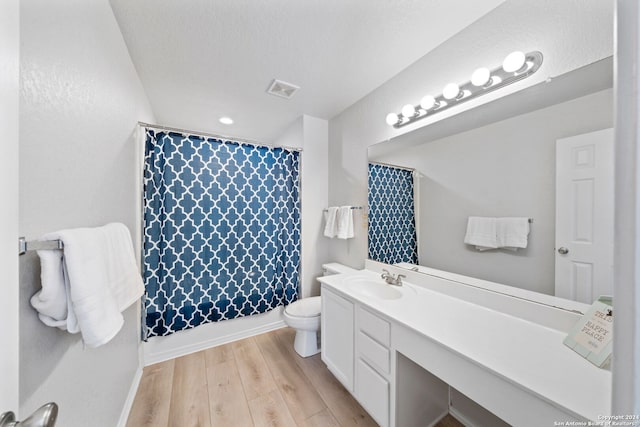 full bathroom with hardwood / wood-style floors, vanity, shower / bath combo, and toilet