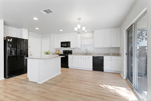 kitchen with sink, decorative light fixtures, light hardwood / wood-style floors, and black appliances