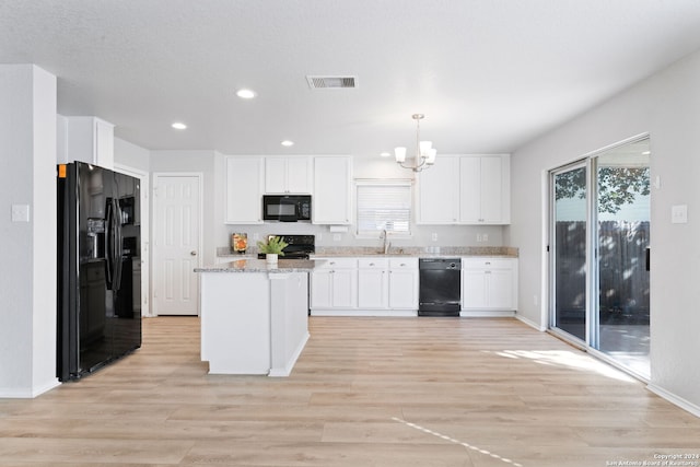 kitchen with black appliances, plenty of natural light, pendant lighting, and white cabinets