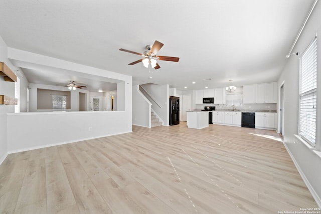 unfurnished living room with light wood-type flooring, ceiling fan, and sink