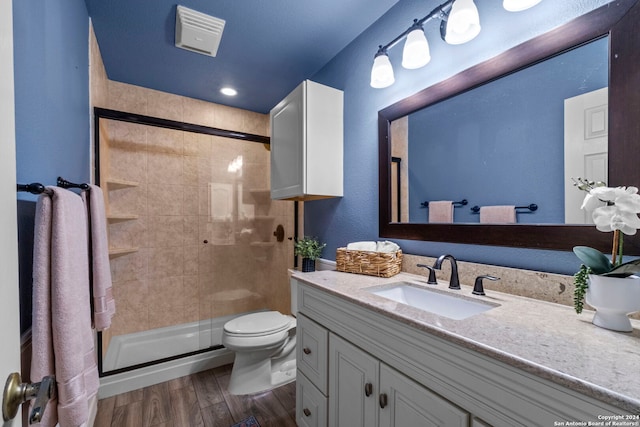 bathroom with hardwood / wood-style floors, vanity, an enclosed shower, and toilet