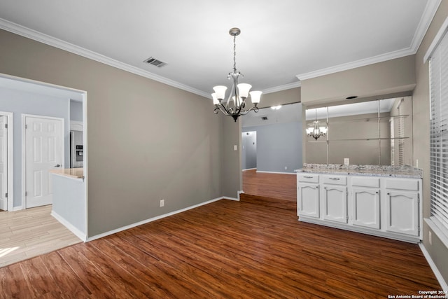 unfurnished dining area with light wood-type flooring, ornamental molding, and an inviting chandelier