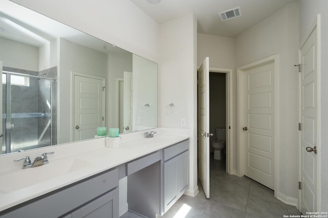 bathroom with tile patterned flooring, vanity, toilet, and walk in shower