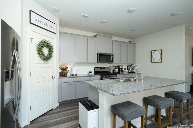 kitchen featuring light stone countertops, sink, stainless steel appliances, dark hardwood / wood-style flooring, and gray cabinets