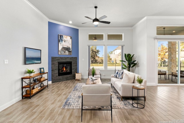 living room featuring a tile fireplace, ceiling fan, light wood-type flooring, and ornamental molding