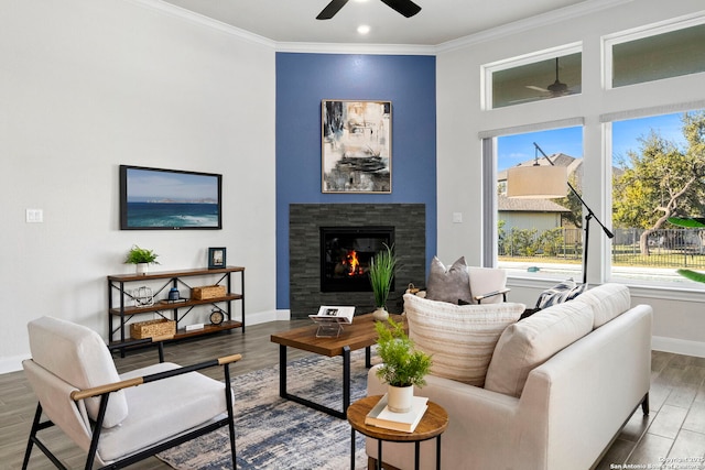 living room featuring ceiling fan, wood-type flooring, a fireplace, and ornamental molding