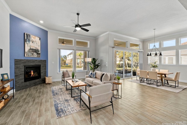 living room with hardwood / wood-style floors, ceiling fan, ornamental molding, and a tiled fireplace