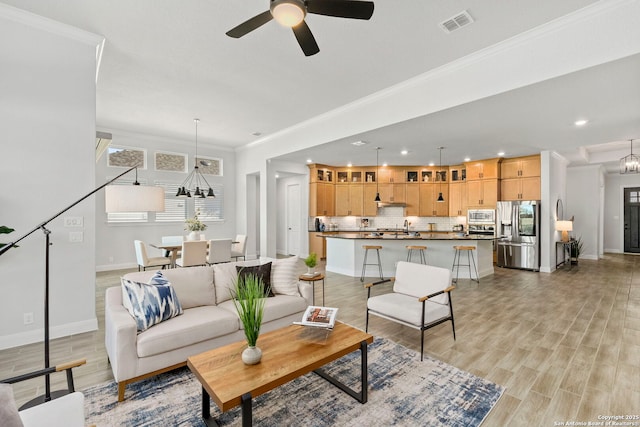 living room with crown molding, light hardwood / wood-style flooring, and ceiling fan with notable chandelier