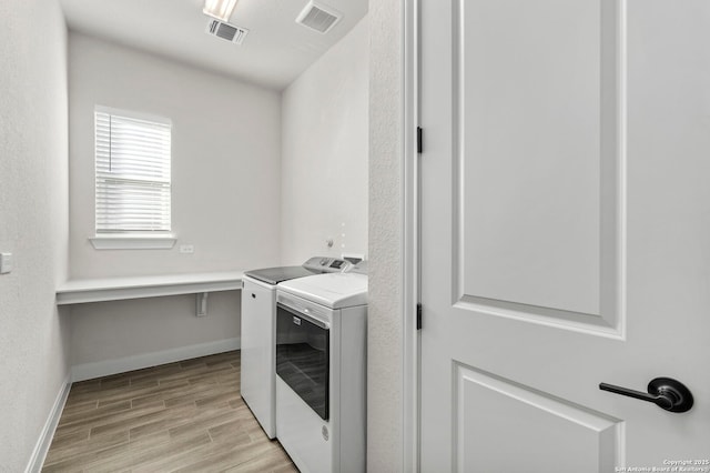 clothes washing area with light hardwood / wood-style floors and washer and clothes dryer