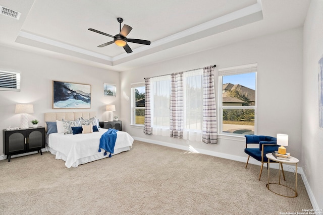 bedroom featuring a tray ceiling, multiple windows, ceiling fan, and carpet floors