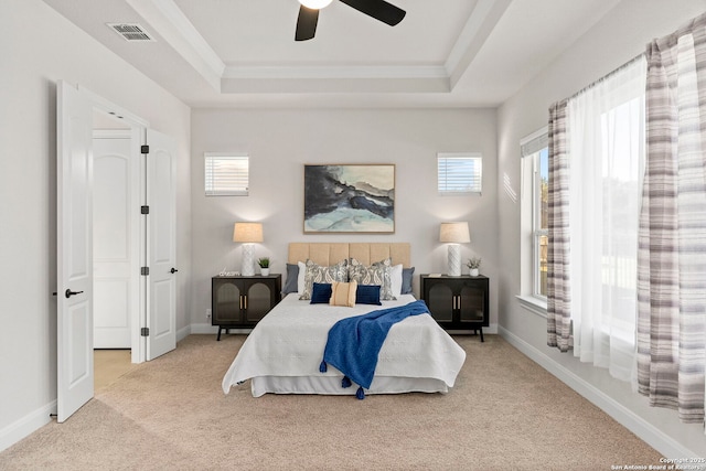 carpeted bedroom with a tray ceiling and ceiling fan