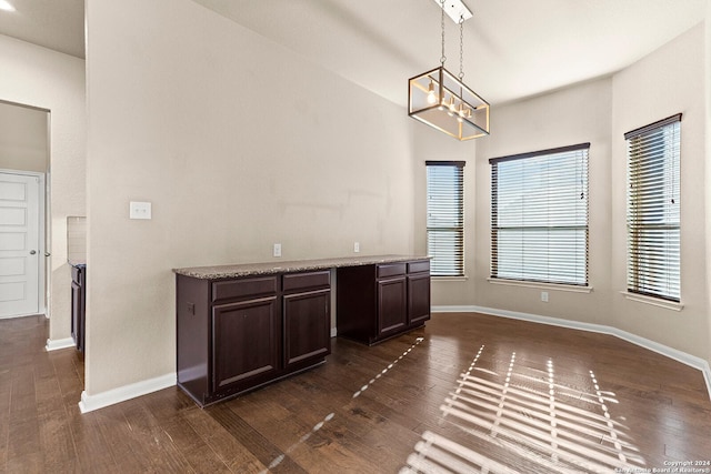 unfurnished dining area with a notable chandelier and dark wood-type flooring